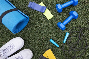 Yeşil çim arka planda fitness ekipmanları. Spor malzemeleri, çimlerin üzerinde spor aksesuarları. Spor anlayışı, spor anlayışı, sağlıklı yaşam tarzı.