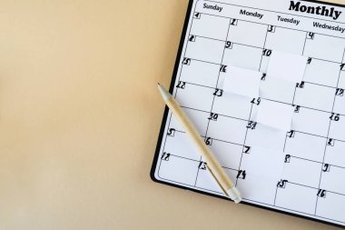 Takvim. Yapışkan notlu takvim sayfası, bej arkaplanlı kalem, üst görünüm. Mesaj için yer var. Planlayıcı.