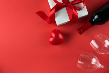 Kırmızı arka planda şarap şişesi ve hediye kutusu, 14 Şubat konsepti.