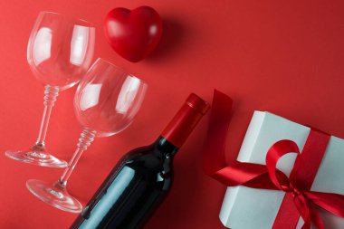 Kırmızı arka planda şarap şişesi ve hediye kutusu, 14 Şubat konsepti.