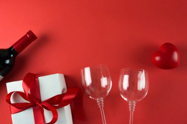 Kırmızı arka planda şarap şişesi ve hediye kutusu, 14 Şubat konsepti.