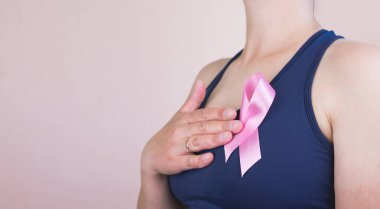Pembe arka planda pembe kurdele tutan genç bir kadın ve mesaj için yeri var. Göğüs kanseri farkındalığı konsepti
