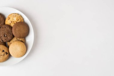 Beyaz arka planda beyaz tabakta farklı yuvarlak kurabiyeler. Üst görünüm.