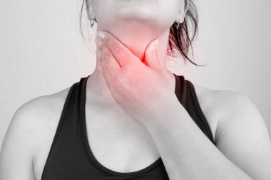 Boğazı ağrıyan, boynu ağrıyan, boş yere dokunan, siyah beyaz fotoğraf çeken bir kadının yakın çekimi.