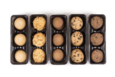 Açık bir kutuda çeşitli yuvarlak kurabiyeler. Kurabiyeler beyaz pakette, biberler kabın içinde.