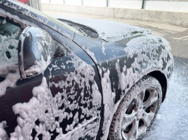 Oto yıkamada köpükle kaplı bir arabanın yakın çekimi..