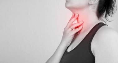 Boğazı ağrıyan, boynu ağrıyan, boş yere dokunan, siyah beyaz fotoğraf çeken bir kadının yakın çekimi.