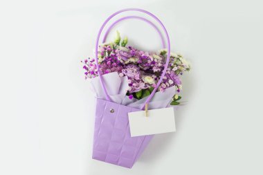 Beyaz arka planda hediye paketinde farklı mor çiçeklerden oluşan bir buket. Bayram hediyesi, Kadınlar Günü, Düğün. Hediye paketinde çiçek aranjmanı. Şablon.