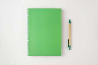 beyaz arkaplanda izole edilmiş yeşil defter ve kalem