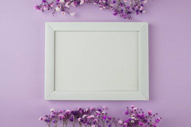 Mor pastel arka planda çiçeklerle süslenmiş fotoğraf çerçevesi. Metin için boş alan. Kopyalama alanı olan bir model. Düz yatıyordu. Beyaz fotoğraf çerçevesi, afiş. Kartpostal, Anneler Günü, 8 Mart.