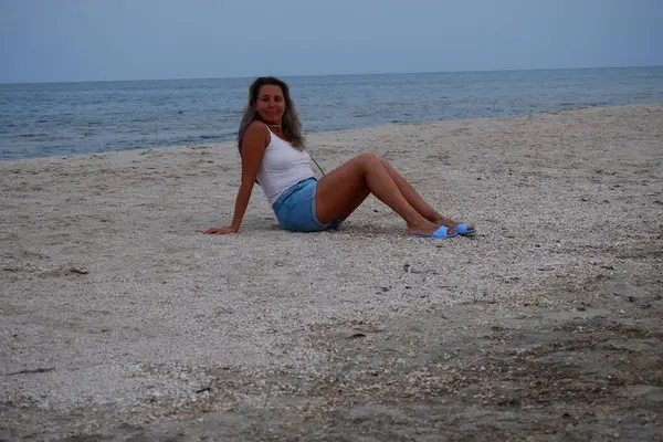 Tatil kumsalındaki kadın fotoğraf çekimi yapıyor farklı pozlar ve mekanlarda gülümsüyor sarı saçlı hasır şapka farklı çekim seçenekleri sunuyor güneşlenmeler deniz ve kumda yürüyor.