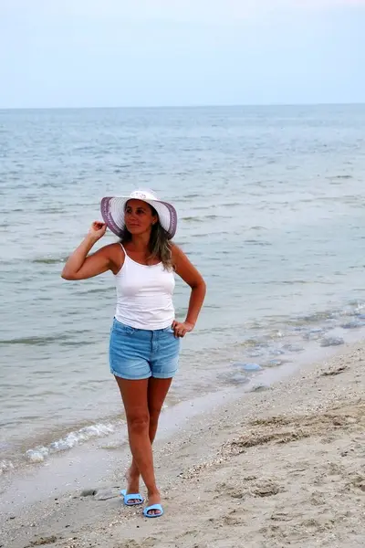 Deniz kıyısında şapkalı bir kadın..