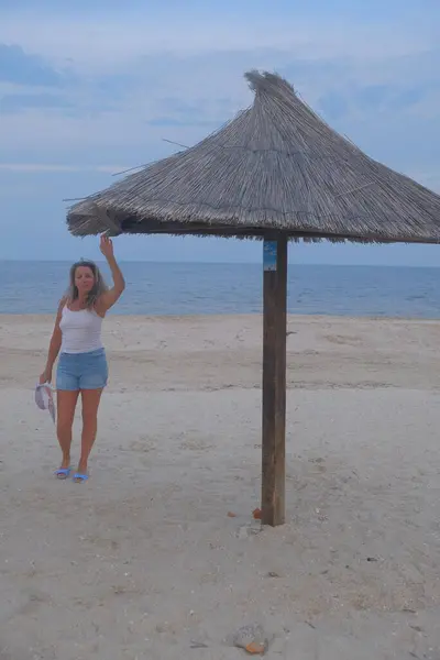 Sahilde hasır şapkalı bir kadın.