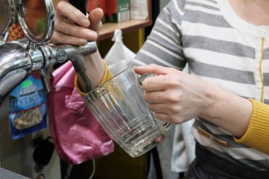 Kadın bardağa temiz içki döküyor.