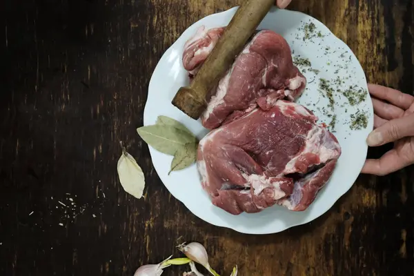 Ahşap arka planda baharatlı ve otlu çiğ domuz pirzolası. Yemek pişirmek. en üstteki görünüm.