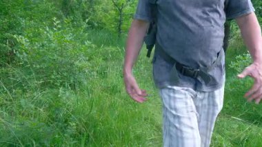 Ormanda orta yaşlı bir adam kareli şortlu ve beyaz şapkalı turistle yürürken yavaşça hava soluyor. Yüksek kalite 4k görüntü