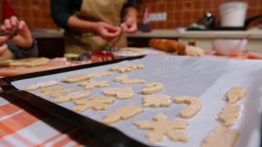 Kızıyla evde mutfakta Noel pastaları hazırlarken bir yandan da zencefilli ekmek hamuru kalıbı koyan bir ev kadınının bulanık arka planına odaklan.