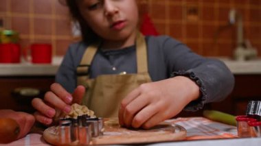 Evde, mutfakta Noel pastası yaparken kurabiye keskisi kullanan, zencefilli kurabiye hamurundan kar taneleri oyan küçük kızların yakın çekimleri. Seçici odak
