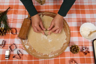 Kadın şefin ellerine bakın. Zencefilli ekmek hamurunun üzerinde kalp şeklinde bir kalıp kesiyor, Noel için ev yapımı hamur işleri yapıyor..