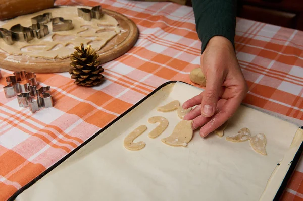 シェフの菓子職人の手は オーブンでクッキーを焼く前に 羊皮紙の上に杖状のジンジャーブレッド生地を入れてください クリスマス休暇のための自家製おいしいお祝いのペストリーの準備 — ストック写真