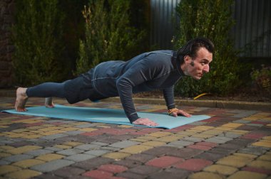 Sporcu, fitness minderinde şınav çekiyor. Erkek yogi gün batımında dışarıda yoga yapıyor. Fiziksel egzersizler. Sağlıklı aktif yaşam tarzı konsepti. Sağlık ve vücut bakımı. Fitness Spor Antrenmanı Farkındalığı.