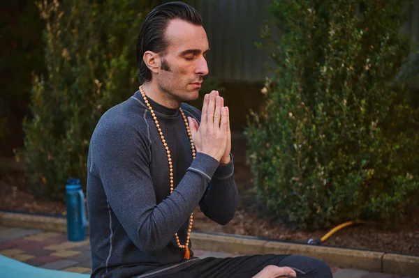 Close-up portrait of peaceful man yogi practicing yoga outdoors, meditating, putting palms together. Meditation. Yoga practice. Mindfulness. Prayer and gratitude. Spiritual growth. Health. Body care