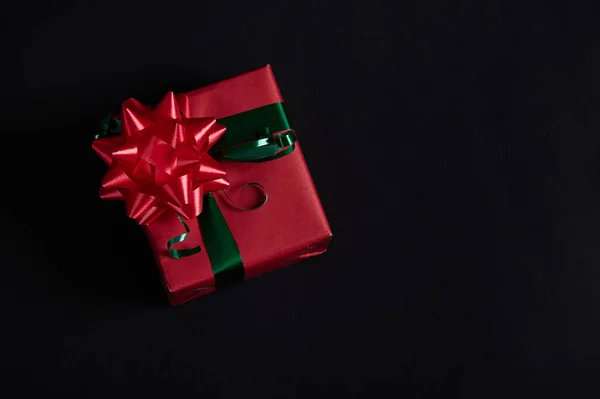 静谧的生活 圣诞礼物装在礼品盒里 用红色包装纸包裹 绿色缎带和黑色背景的红色系带蝴蝶结 平躺在床上12月25日 圣诞佳节快乐 — 图库照片