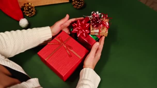 ベージュのセーターを着たトップビューの女性は クリスマスツリーの形でギフトボックスをレイアウトします ボクシングの日 光沢のあるリボンと弓で縛られた鹿のパターンと赤の色で包装紙に包まれたプレゼント — ストック動画