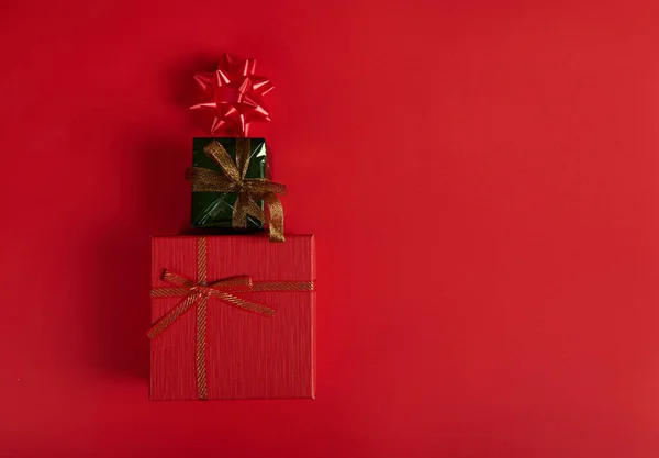 平躺在床上水平工作室拍摄的时尚礼品盒包在红色和绿色包装纸 摆设成圣诞树的形状 装饰着红色背景的蝴蝶结 复制空间 静静生活 — 图库照片