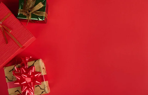 顶部视图 圣诞和新年礼品盒红色背景与复制广告空间 用鹿纹包装纸包裹礼物的软垫 红绿相间的颜色和打结的蝴蝶结 — 图库照片