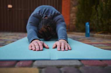 Yoga yaparken vücudunu esnetirken erkek sporcunun ellerine ya da spor minderindeki yogilere odaklan. Esniyorum. Spor. Fitness. Sağlık ve vücut bakımı. Vücut bilinci. Aktif sağlıklı yaşam tarzı