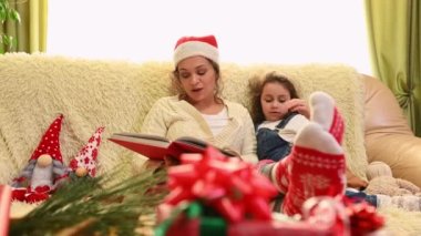 Mutlu bir kadın ve kızı evde birlikte Noel tatili geçiriyorlar. Sevimli küçük kız annesinin peri masalları okumasını, bir kanepede yan yana oturmasını dinliyor. Önplanda bulanık hediyeler