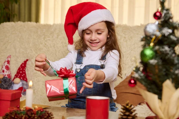 Glücklich Verschmitztes Kleines Mädchen Mit Santas Hut Packt Hause Das — Stockfoto