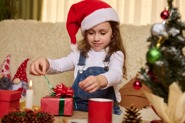 Девочка Красной Шляпе Сантаса Распаковывает Милую Подарочную Коробку Сюрпризом Рождество — стоковое фото