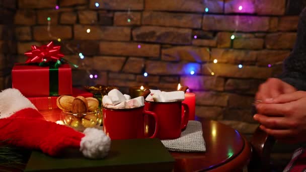 魅力的な多民族の女性のクローズアップ肖像は クリスマスの居心地の良い家のインテリアのテーブルに座って マシュマロとホットチョコレートやココアを飲んでいます 冬休みだ 12月25日 明けましておめでとうございます — ストック動画