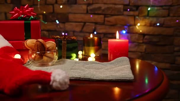 特写镜头下 女性的手将红杯 热巧克力饮料和棉花糖放在木制桌子上 桌上有圣诞装饰品 烤饼干和点燃的蜡烛 圣诞室内点着烛光 — 图库视频影像