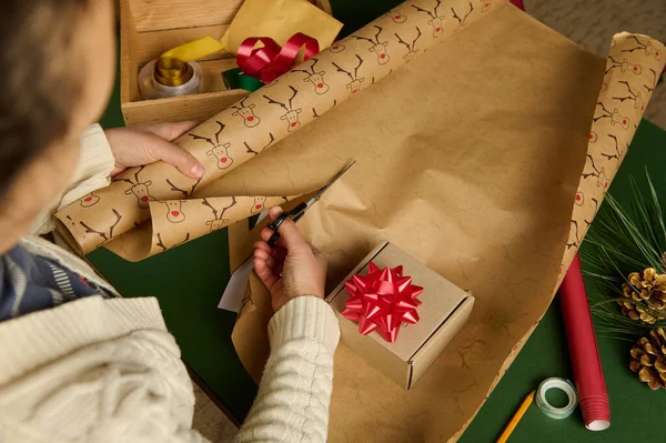 Makas kullanan tanınmayan bir kadının genel görünüşü Noel, yeni yıl ya da başka bir kutlama etkinliği için dekoratif ambalaj kağıdını keser. El sworkart. Boks Günü. İşte hediyeler.