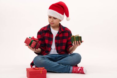 Beyaz arka planda, fotokopi reklam alanı olan izole edilmiş bir portre. Noel Baba şapkası takan sevimli, mutlu bir beyaz çocuk. Noel ya da yeni yıl hediyesi. Boks Günü. Aralık