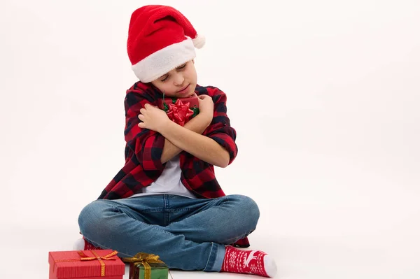 Entzückender Junge Mit Weihnachtsmütze Sanft Umarmt Ein Weihnachtsgeschenk Isoliert Über — Stockfoto