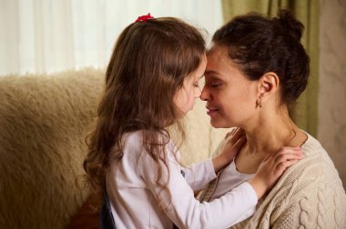 Sevimli bir kadın, sevgi dolu bir anne ve kız birbirlerine sarılıyorlar, alınları birbirine yaslanmış. Kaygısız çocukluğun kutlu olsun. Bilinçli annelik. Aile sevgisi. Şefkat, ilgi, şefkat.