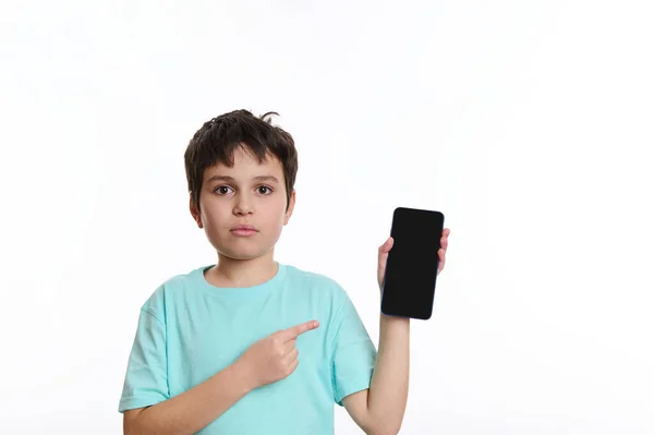 Chłopiec Niebieskiej Koszulce Wskazuje Smartfona Pustym Ekranem Reklamy Lub Aplikacji — Zdjęcie stockowe