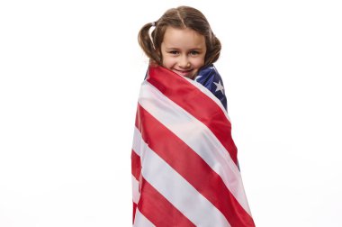 Güzel vatansever Amerikan vatandaşı, Bağımsızlık Günü 'nde Amerikan bayrağına sarılı iki at kuyruklu sevimli küçük bir kız çocuğu - 4 Temmuz, beyaz arka planda izole bir şekilde kameraya gülümsüyor.