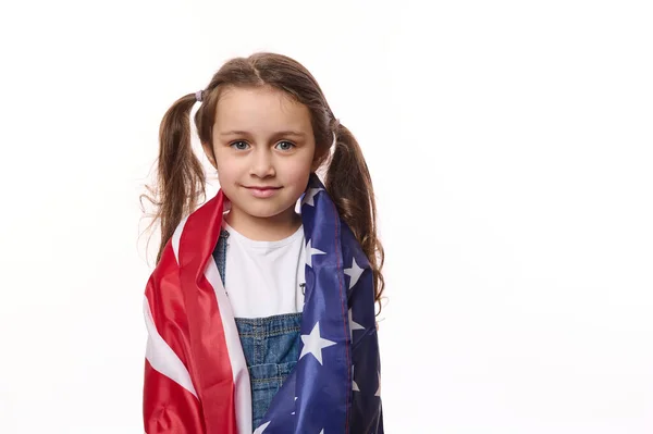 Isolated portrait on white background of beautiful American little girl with USA flag. Citizenship, immigration, emigration, winning the green card lottery and freedom concept. Independence Day July 4