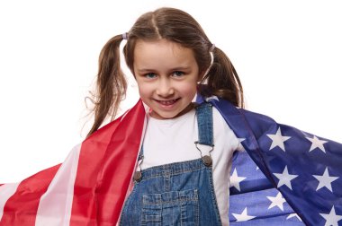 Küçük mutlu bir Amerikan vatandaşı, mavi kot pantolon giymiş şirin bir kız çocuğu, Amerikan bayrağıyla, 4 Temmuz 'da Bağımsızlık Günü' nü kutluyor, beyaz arka planda izole edilmiş. Göçmenlik, vatandaşlık ve özgürlük kavramı