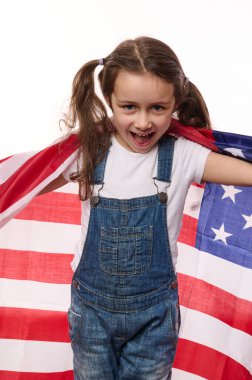 Dikey portre, Amerika Birleşik Devletleri vatandaşının izole edilmiş beyaz arka planı, iki at kuyruklu güzel kız çocuğu, ABD bayrağını saran. Vatandaşlık. Bağımsızlık Günü. Göçmenlik kavramı
