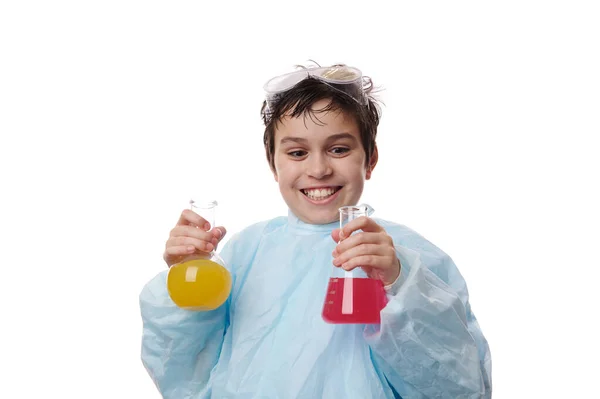 研究室のコートで驚くべき10代の少年は ビーカーからフラスコに溶液を注ぎ 興奮して驚きの表情で化学反応が起こっているのを観察します 化学の奇跡だ 学校に戻る — ストック写真