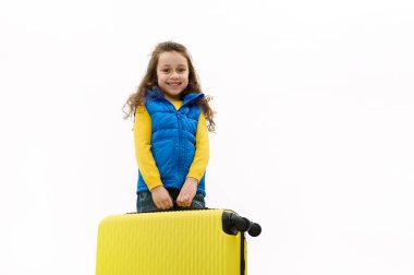 Mutlu, dişlek bir gülümsemeyle gülümseyen, sarı bir bavul taşıyan, hafta sonu kaçamağı yapan ya da sıcak ülkelere seyahat eden mutlu bir kızın beyaz arka planda izole edilmiş portresi. Seyahat kavramı