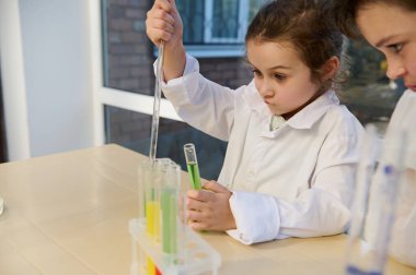 Beyaz laboratuvar önlüğü giymiş, kimyasal deneyler yapan, kimya sınıfındaki bir test tüpüne birkaç reaktör damlatan 5 yaşındaki yaramaz beyaz kız çocuğu. Okul konseptine dönelim.