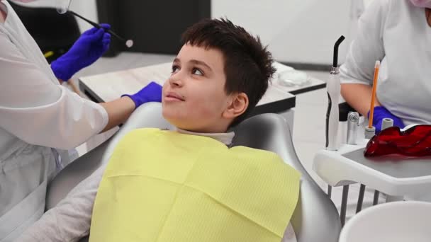 可敬的白人10岁男孩在牙科检查 在现代牙科诊所 牙科医生用牙镜检查坐在牙医椅子上的可爱儿童的牙齿和牙龈 — 图库视频影像