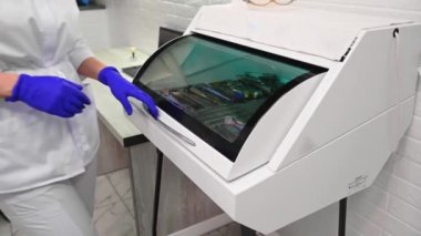 Close-up of dental assistant, doctor dentist hygienist, opening the ultraviolet autoclave sterilizer and taking out sterile stainless steel dental tools. UV thermostat in a modern dentistry clinic.